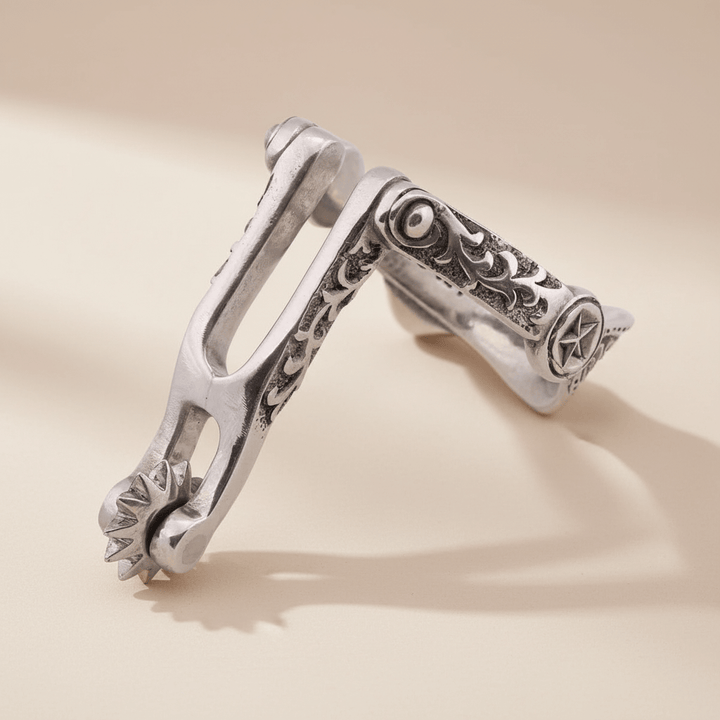 Silver spur napkin ring with intricate designs on a beige background
