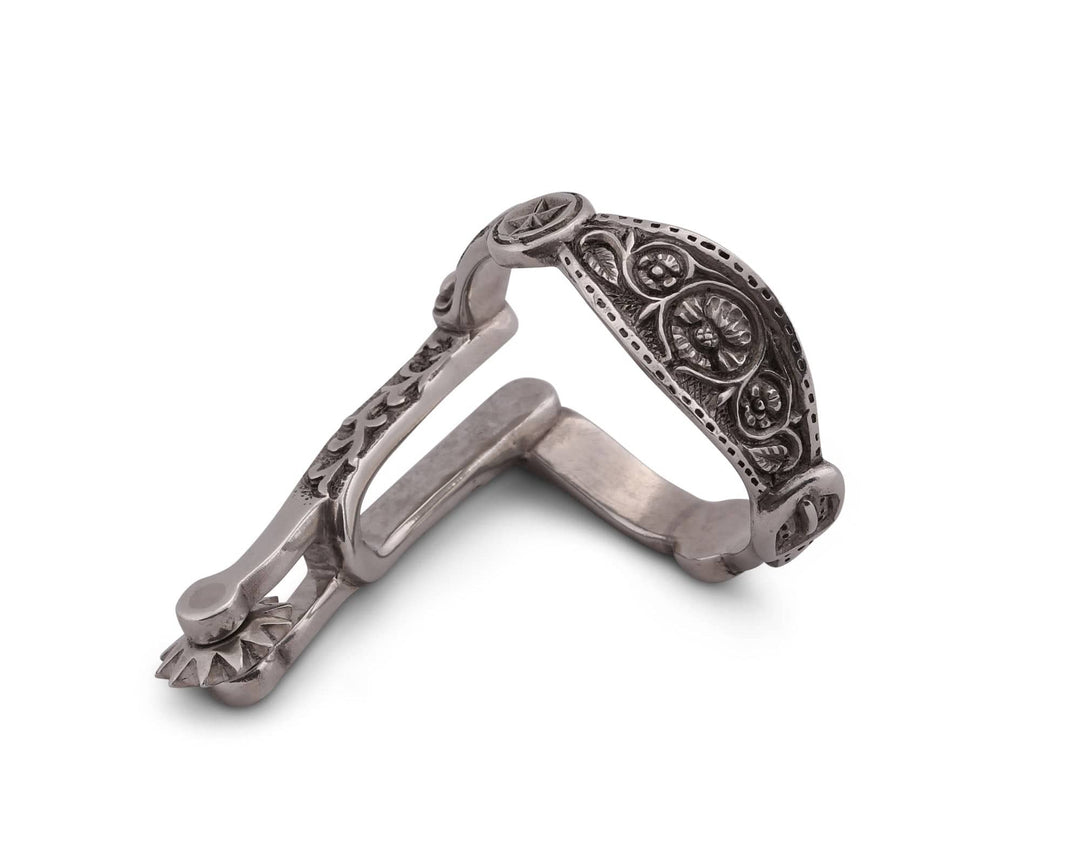 Decorative silver spur napkin ring with intricate designs on a white background