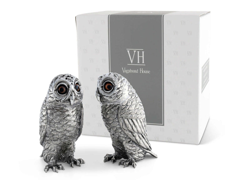 Two silver owl figurines in front of a Vagabond House box on a white background