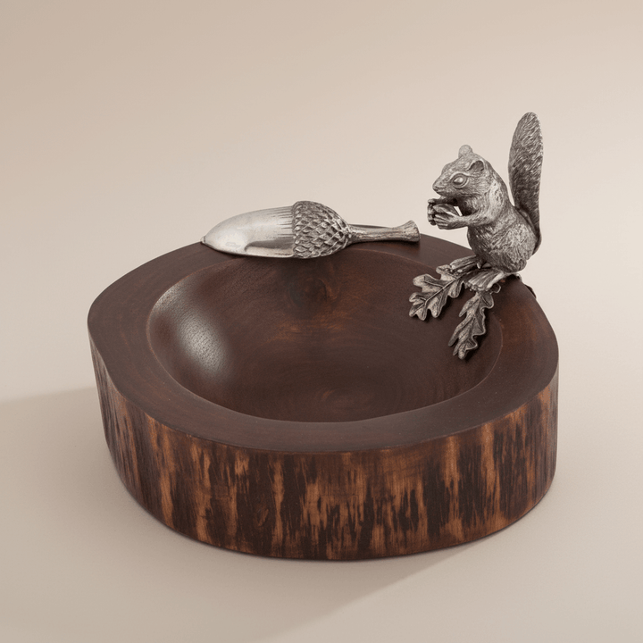 Decorative wooden bowl with metal squirrel and acorn embellishments on a beige background