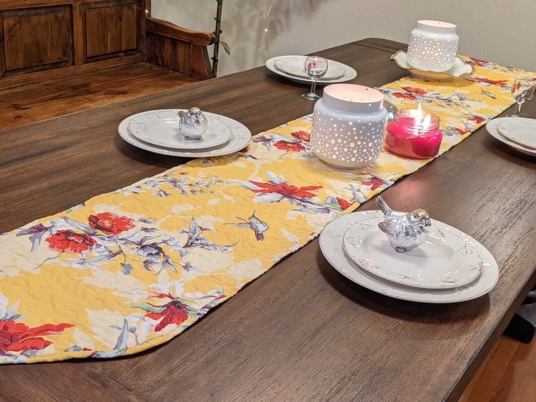 Yellow Floral Vintage Hummingbirds Garden Table Runner (925) on wooden dining table with candles and plates