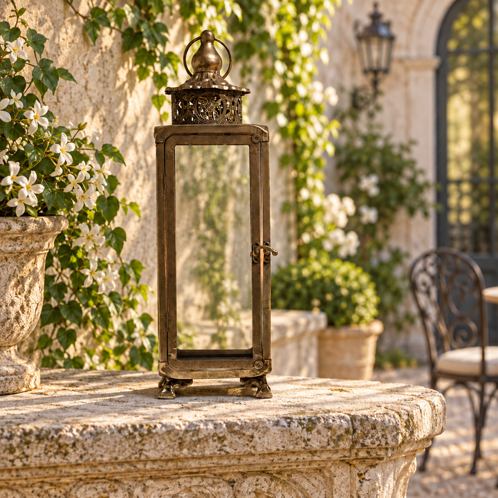 Aged Brass Glass Lantern with Filigree Crown beside greenery at dusk