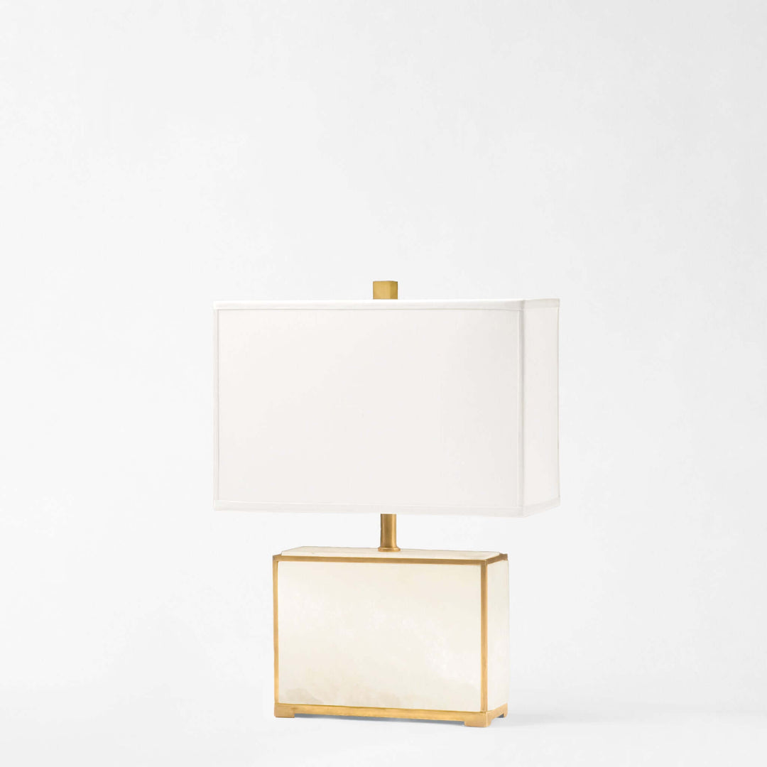Table lamp with gold frame and white shade on a light gray background