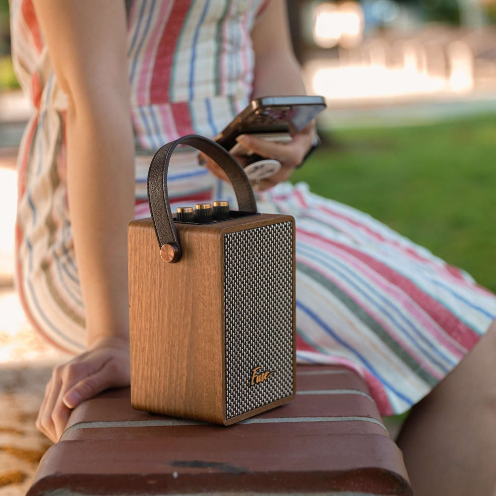 Wooden speaker on a person's lap with a striped dress in the background