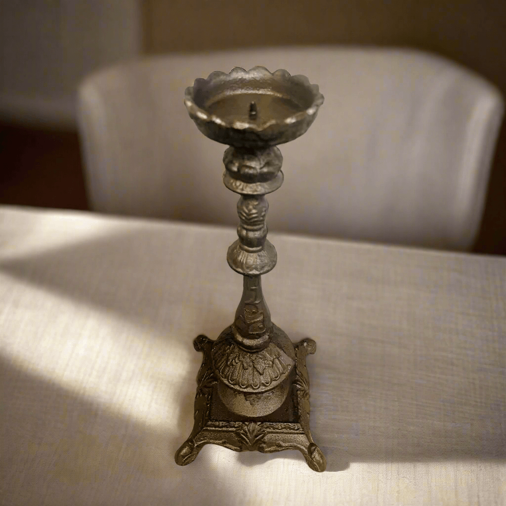 Antique cast iron candle holder with ornate details, perfect for adding vintage elegance to any space.