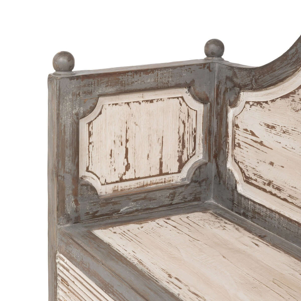Close-up of an antique distressed wood French country bench with decorative panels, capturing rustic elegance and craftsmanship.