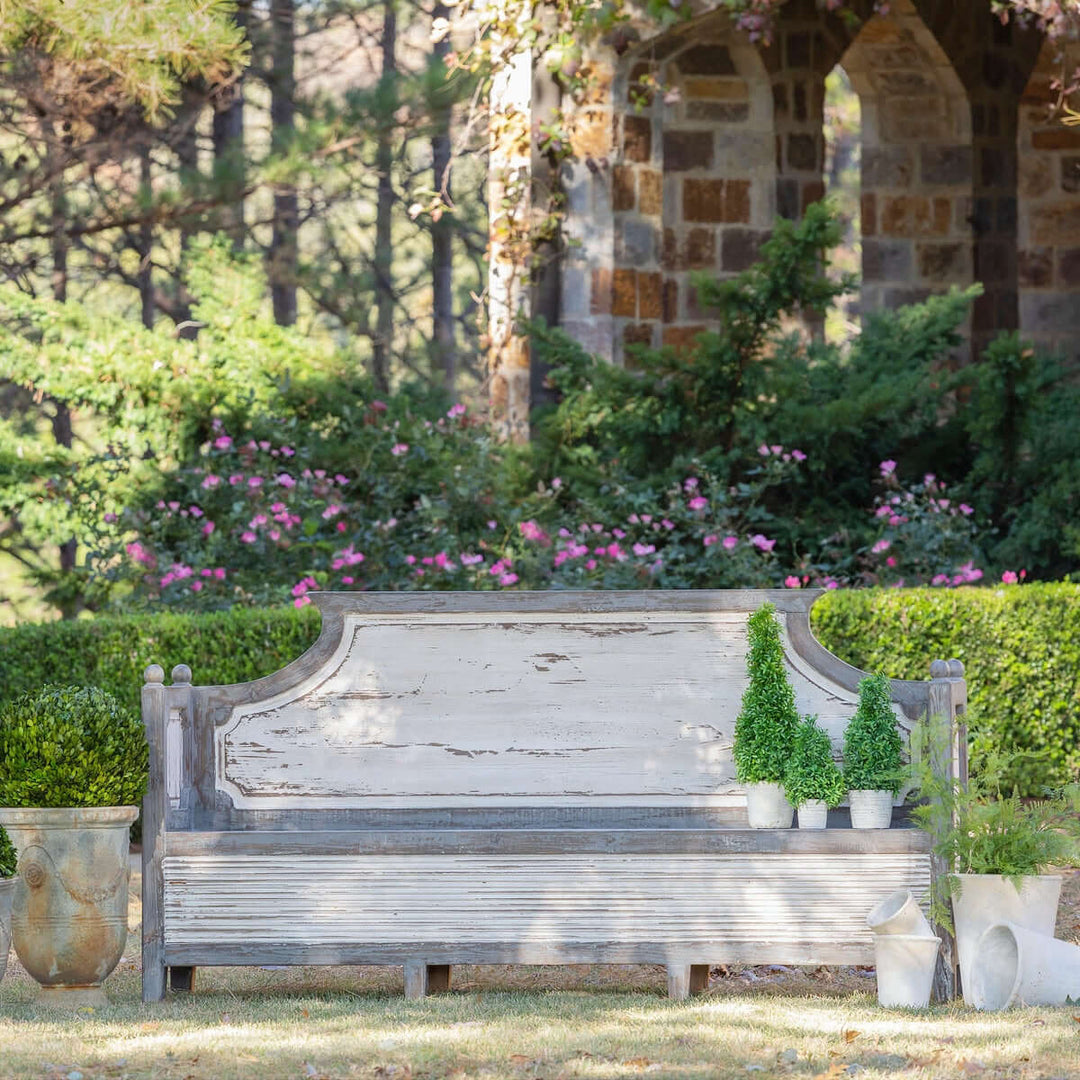 Antique distressed wood French country bench in a garden setting