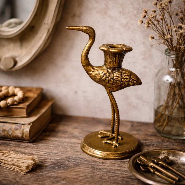 Antique gold crane candle holder on a wood surface, without a candle