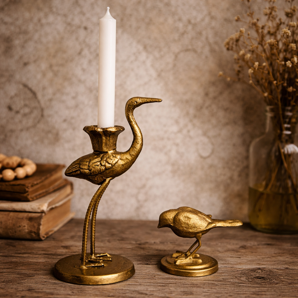 Crane taper holder with a white candle beside a separate small bird ornament