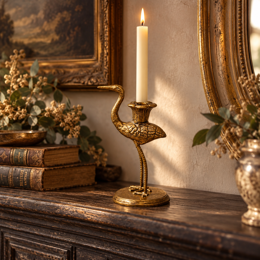 Antique gold crane holder with a lit taper on a dark console