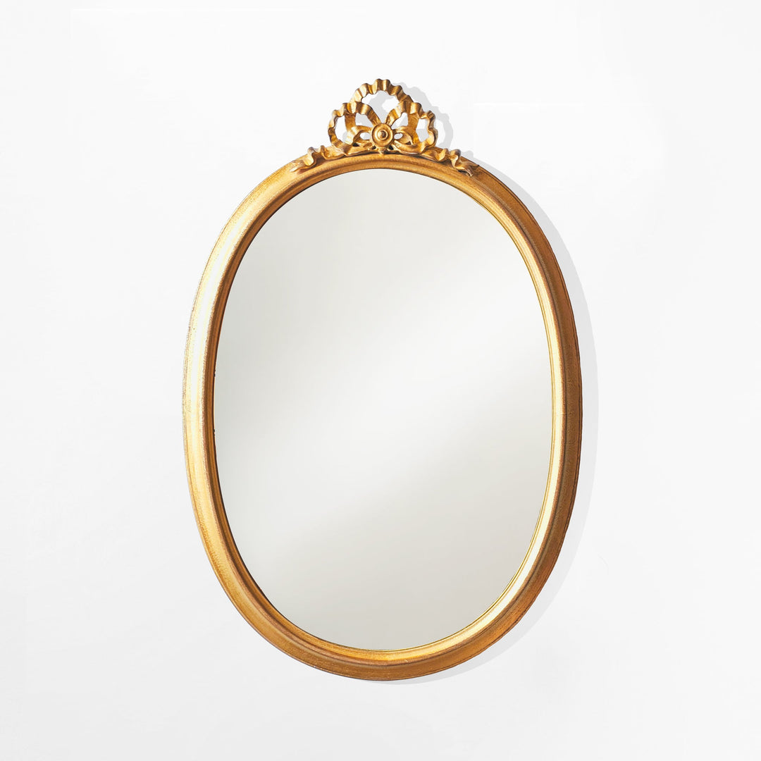 Gold-framed mirror with decorative top on a white background