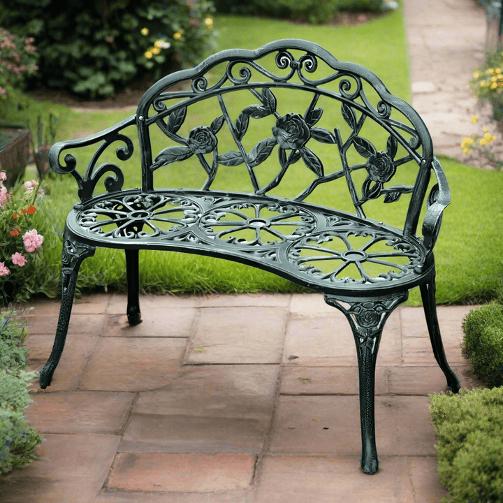 Antique Green Metal Garden Bench with Rose Backrest on a stone patio