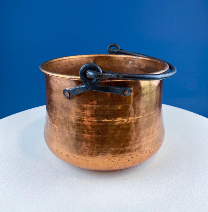 Antique Hand-Hammered Brass Bucket with Wrought Iron Handle: Rustic Farmhouse Decor on a white table.