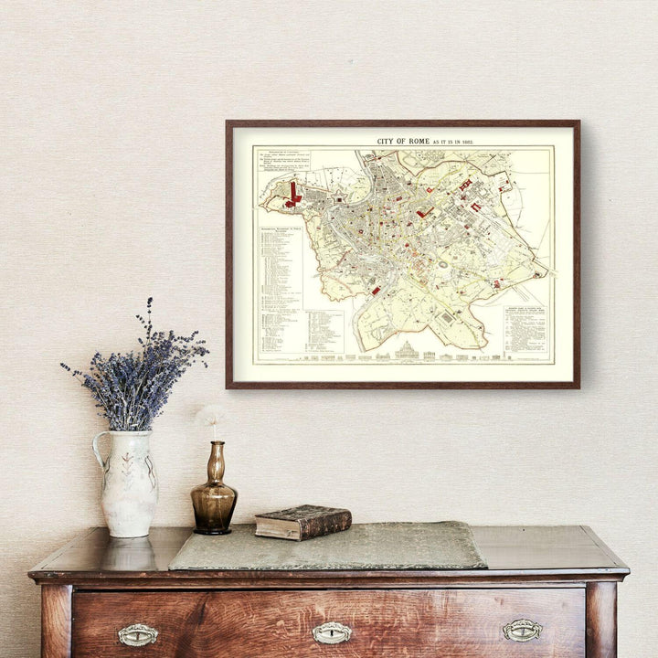 Antique Map of Rome, Italy from 1883 showcased in elegant wood frame on wall above a vintage wooden dresser with decorative vase and books.