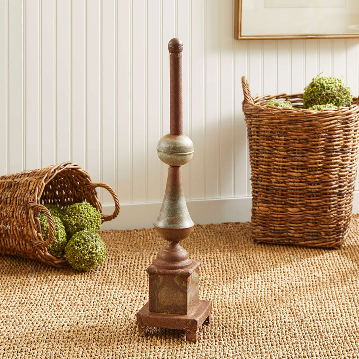 Antique-style rusted metal finial decor adding vintage charm to home interiors with woven baskets in background.