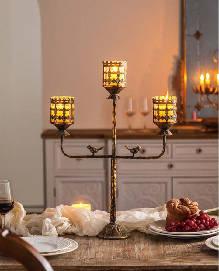 Antique amber glass votive candle holder centerpiece on dining table with glowing candles casting elegant shadows