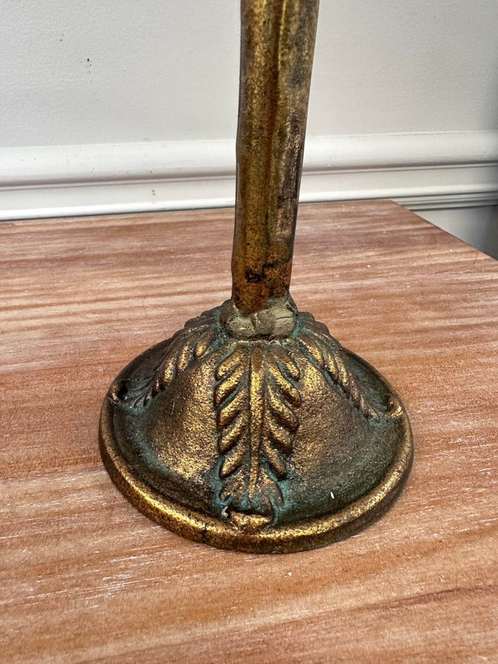 Antique amber glass candle holder base with ornate metalwork design on a wooden table.