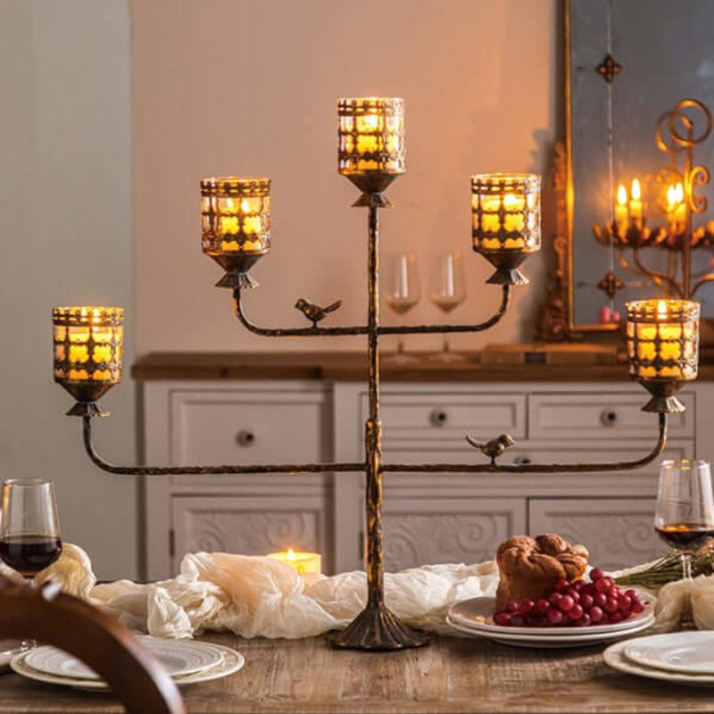 Antique amber glass votive candle holder centerpiece on dining table with glowing candles and elegant dinner setting.