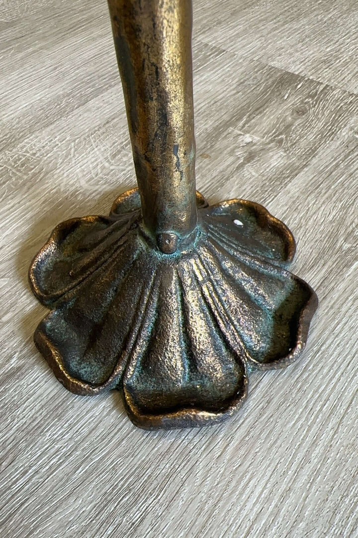 Antique amber glass votive candle holder base with intricate metal latticework on wood floor.