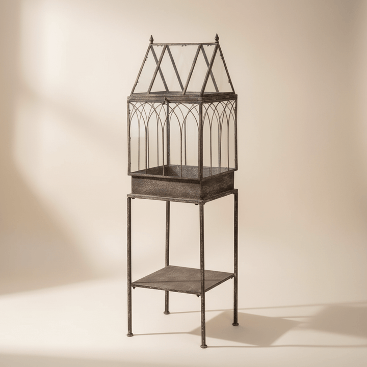 Antique Black Iron Standing Garden Terrarium with Gothic Arch Detail against a beige background