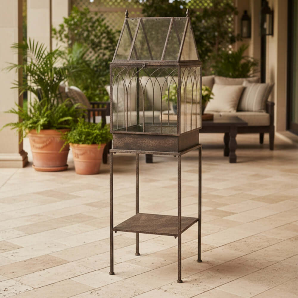 Antique Black Iron Standing Garden Terrarium with Gothic Arch Detail displayed on patio with plants