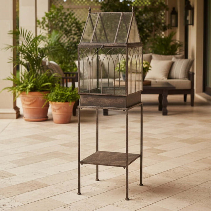 Antique Black Iron Standing Garden Terrarium with Gothic Arch Detail displayed on patio with plants