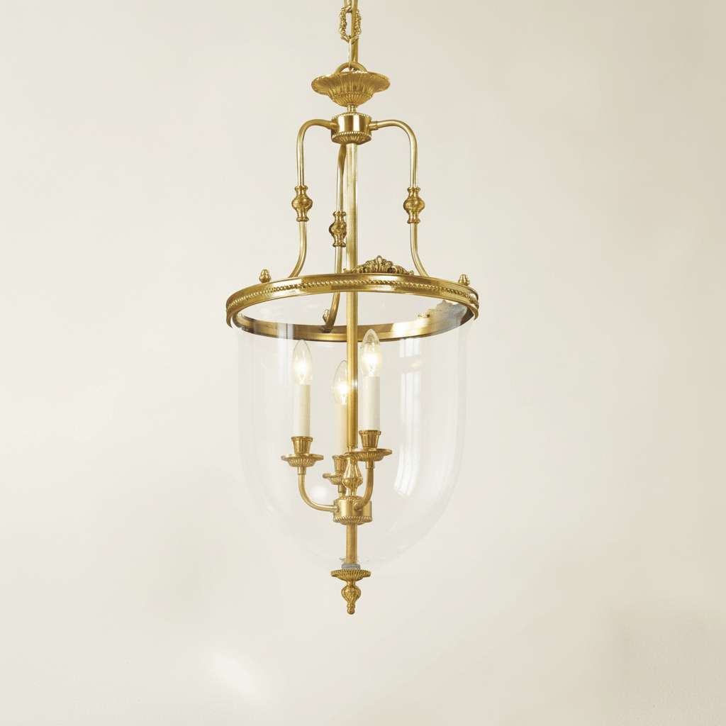 Decorative brass chandelier with clear glass shade on a beige background
