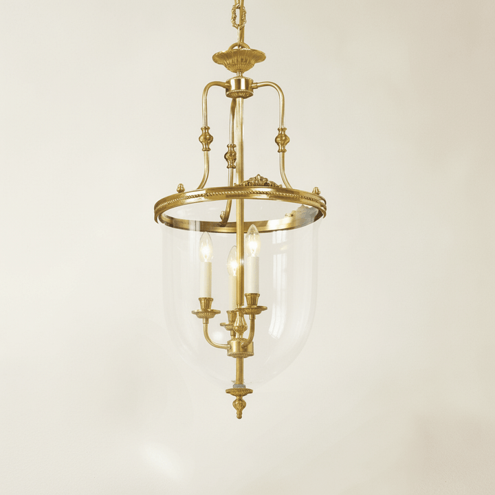 Decorative brass chandelier with clear glass shade on a beige background