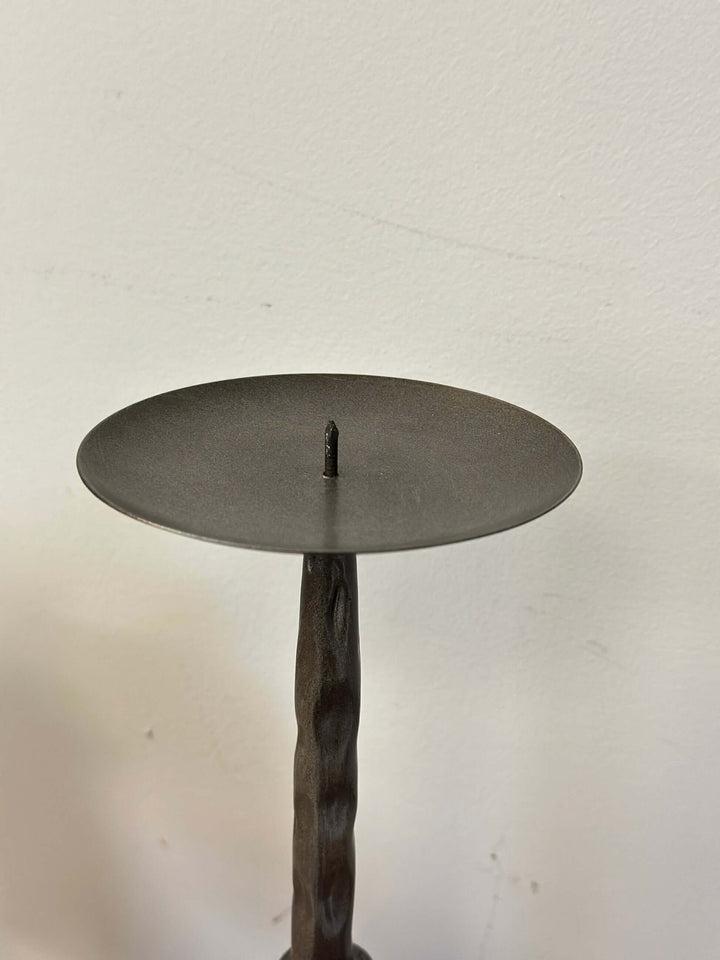 Antique bronze hammered metal candle holder for pillar candles on a textured stand, ideal for creating a nostalgic ambiance.