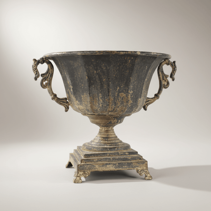 Antique Decorative Urn in Distressed Metal with ornate handles on a pedestal base, showcasing historical charm and elegance.
