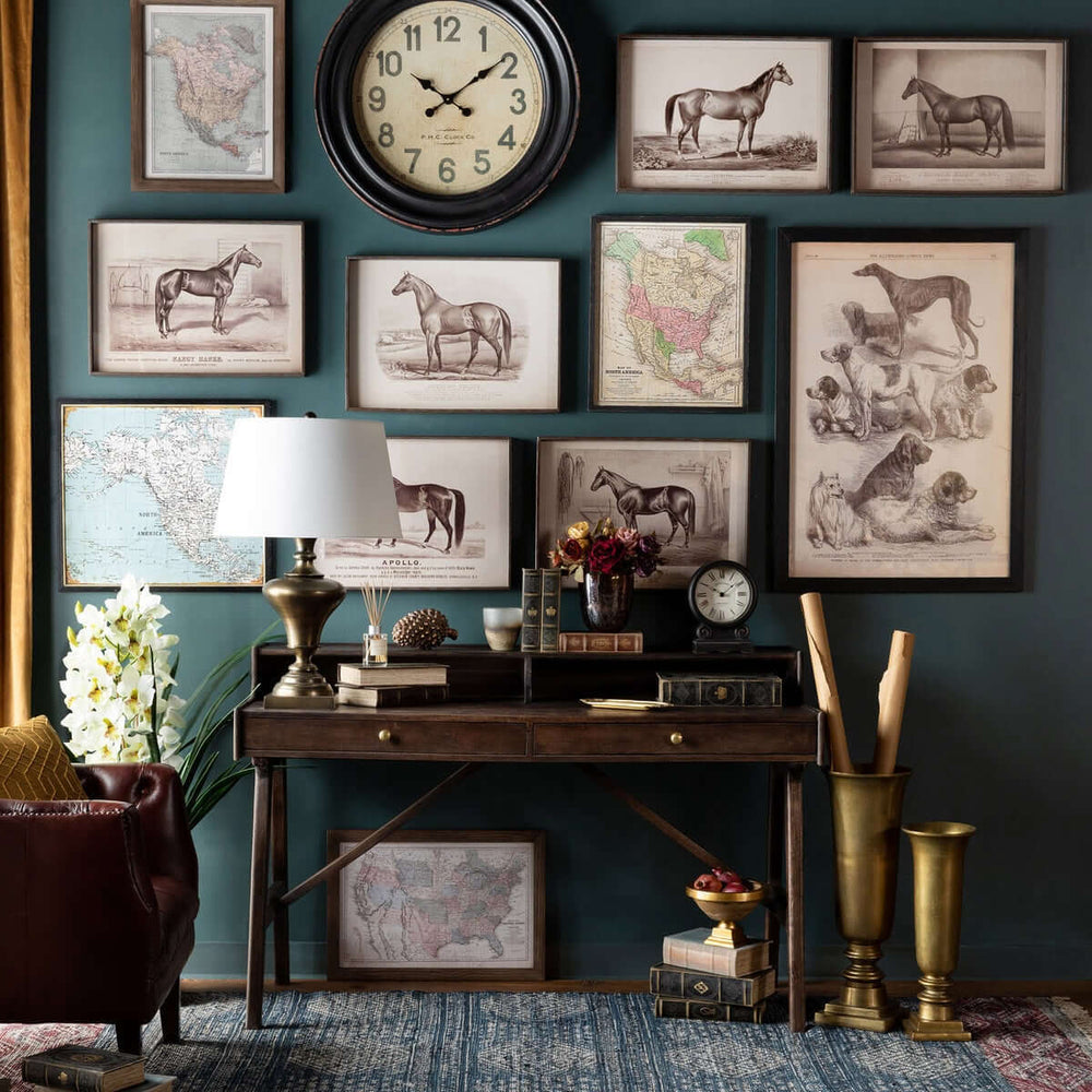 Vintage study room with horse and dog art prints, antique map, and decorative items on a wooden desk against a navy-blue wall.