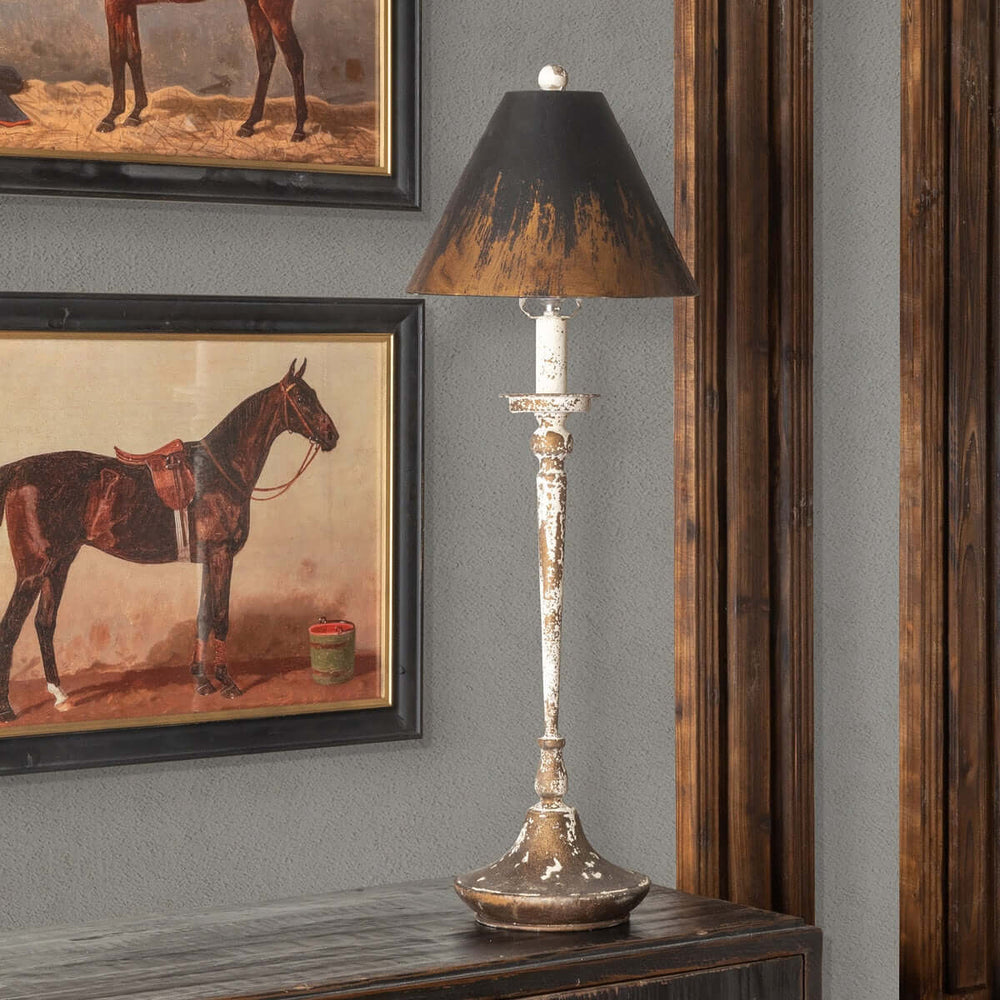 Antique farmhouse distressed buffet lamp on table, casting warm glow.