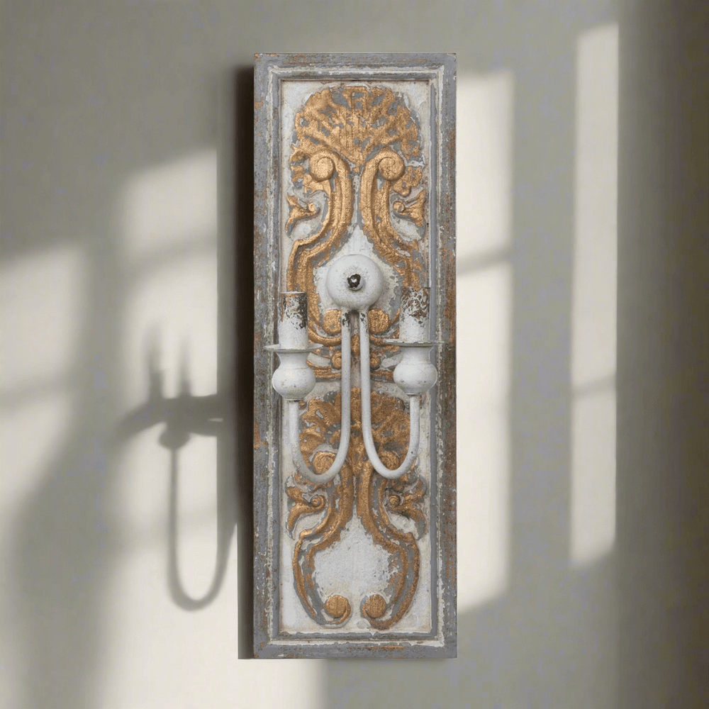 Antique French Country Wall Sconce Light with carved wooden backplate and ornate gold-white finish casting shadow on wall.