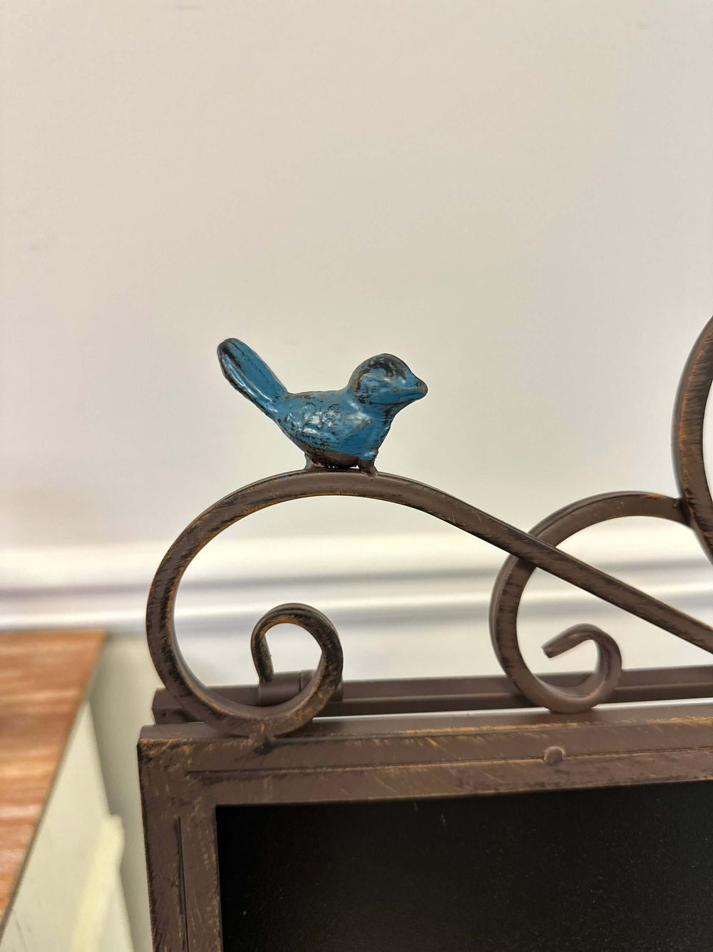 Close-up of bird detail on antique iron chalkboard easel with heart scroll design.