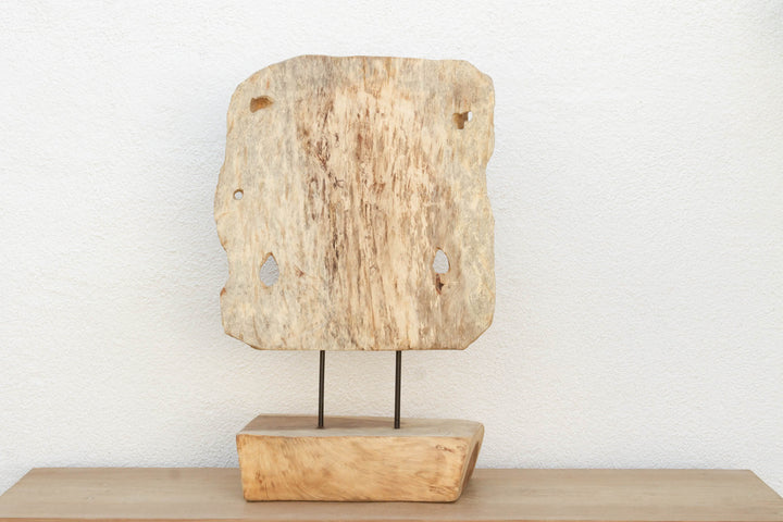 Textured wooden sculpture on a stand against a white background