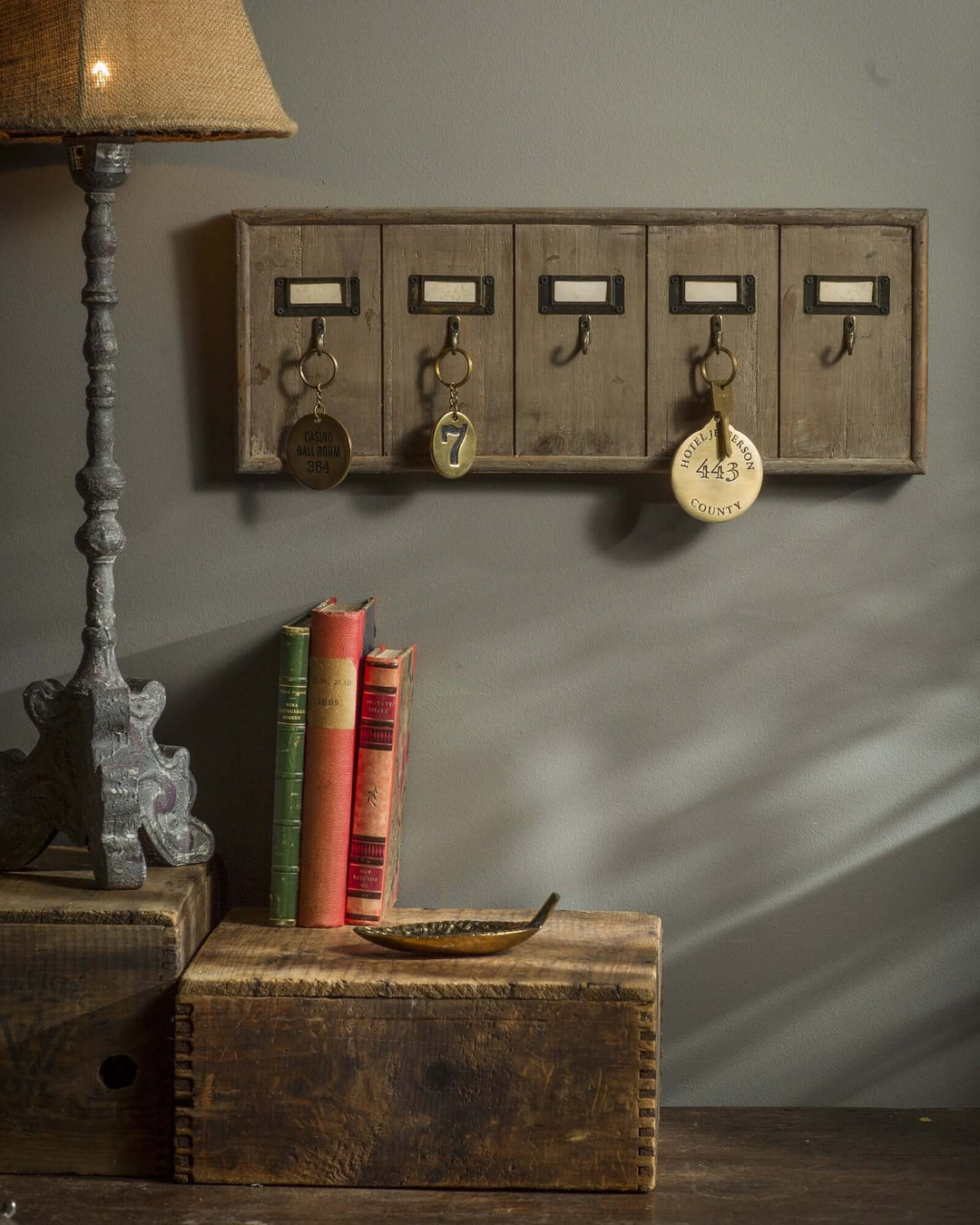 Antique Wooden Hotel Key Rack Organizer with keys on wall beside vintage decor and books
