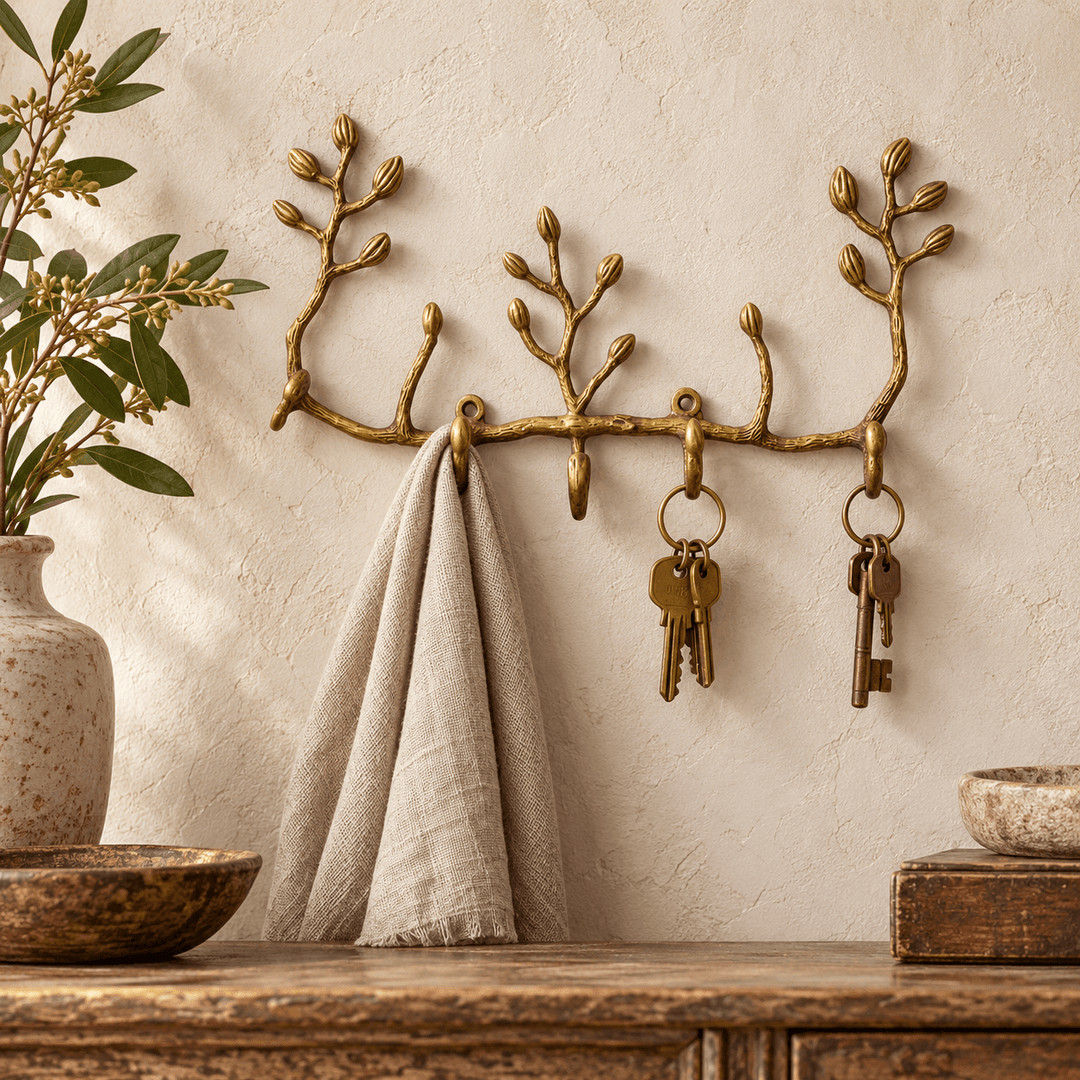 Antiqued brass twig wall key holder with two key rings and a linen scarf above a wood console