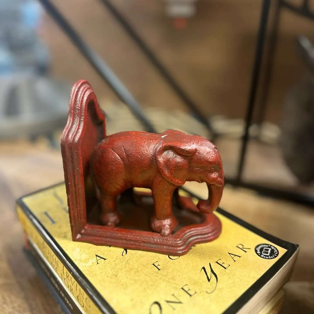 Antiqued red cast iron elephant bookend supporting books