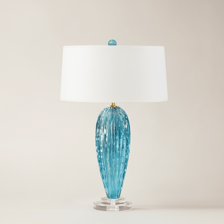 Blue glass table lamp with a white shade on a beige background