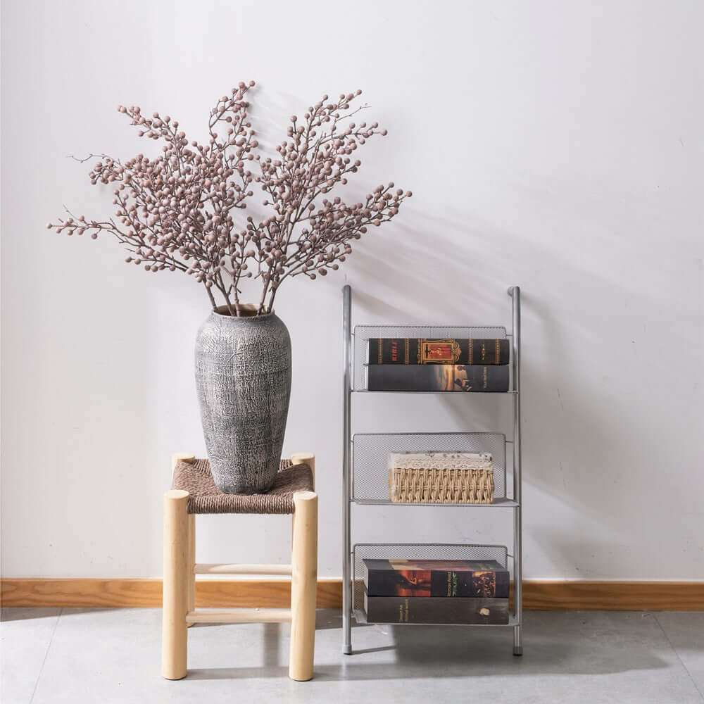 Artificial dried berry branch in gray vase, rustic home decor on wooden and metal shelves.