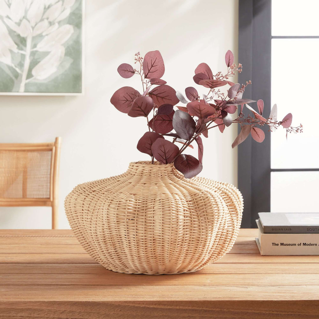 Artisan rattan vase on a table, perfect for boho and coastal décor, showcasing handcrafted design with lush greenery.