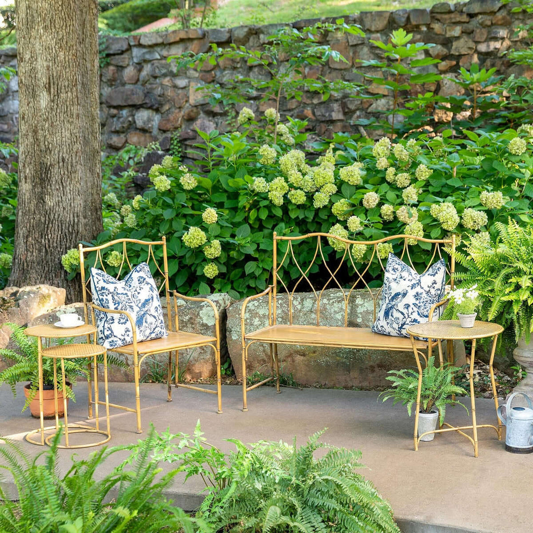 Bamboo style iron nesting tables set on patio with greenery and pillows, showcasing elegant outdoor decor.