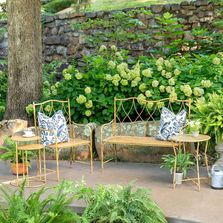 Bamboo style iron nesting tables set on patio with greenery and pillows, showcasing elegant outdoor decor.