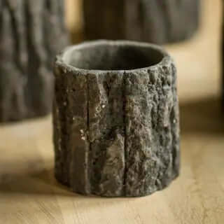Empty small concrete planter showing deep vertical bark grooves