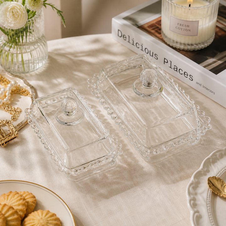 Large and small beaded glass butter dishes on a linen table
