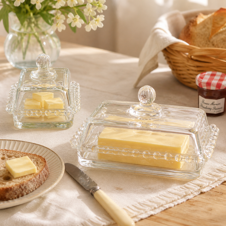Two beaded glass butter dishes with butter at breakfast