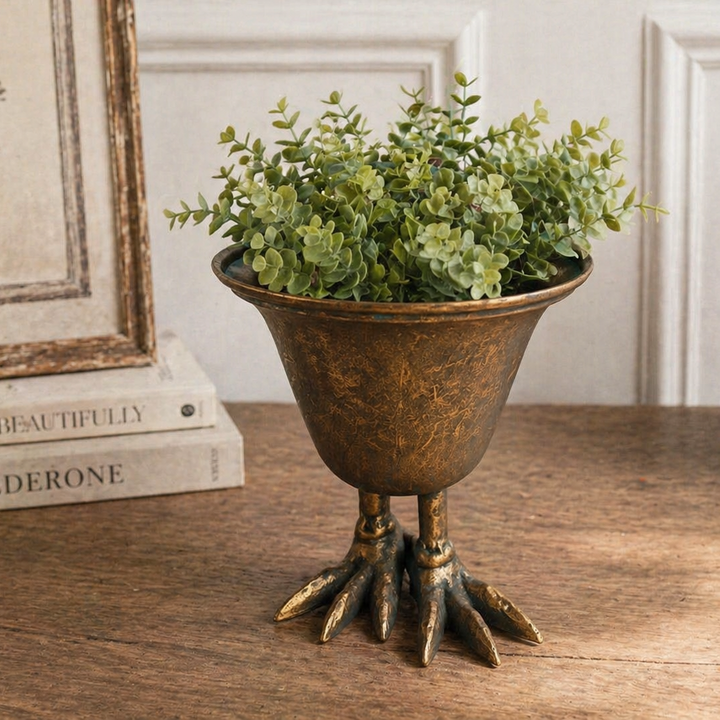Bird Claw Metal Pedestal Planter filled with greenery on a wood console