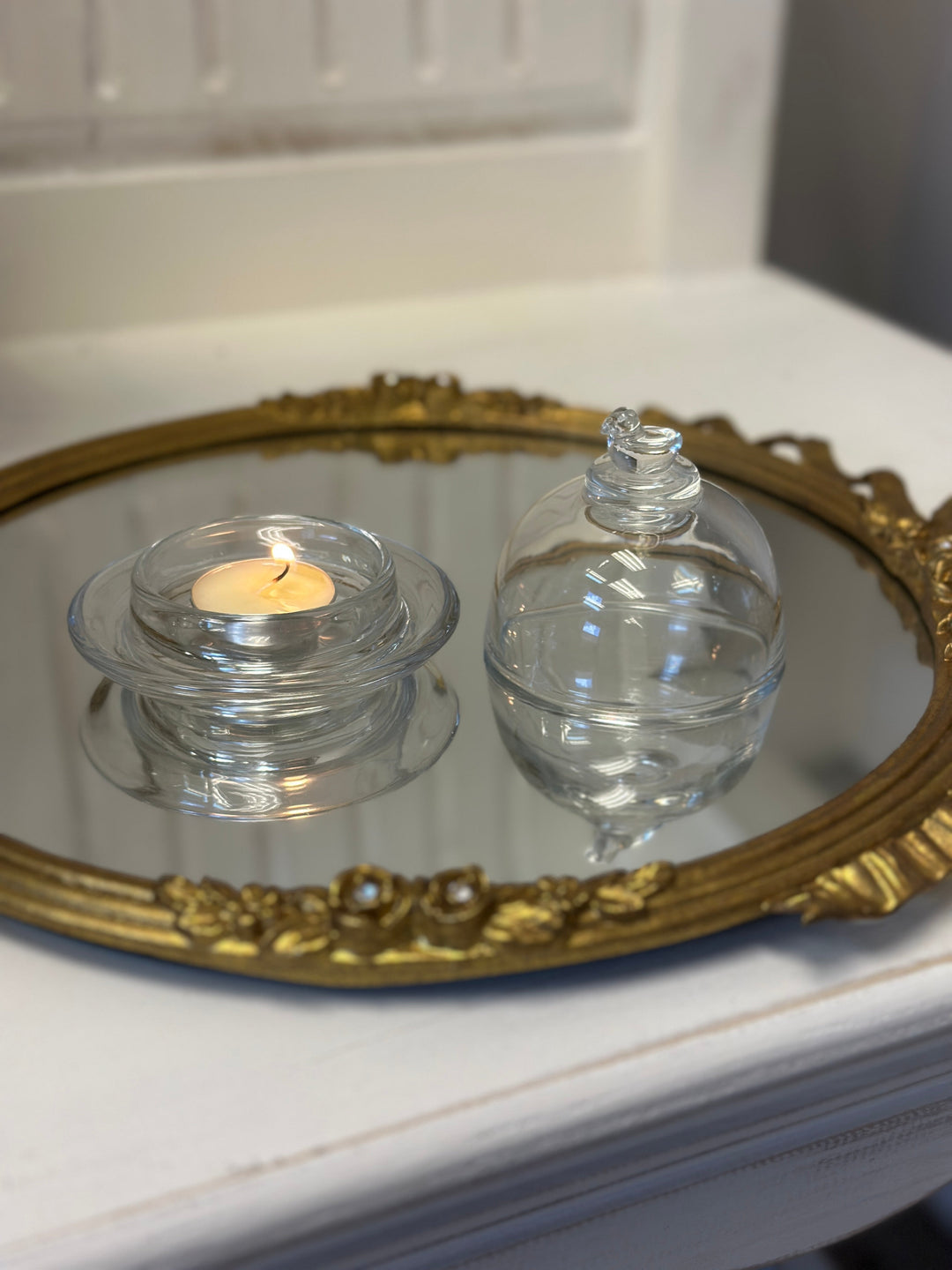 Bird-Topped Glass Cloche covering a glowing tea light on an ornate tray