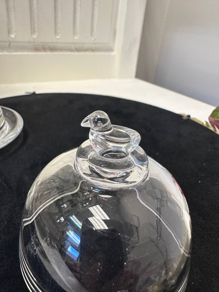 Close view of the sculpted bird finial on the clear glass dome
