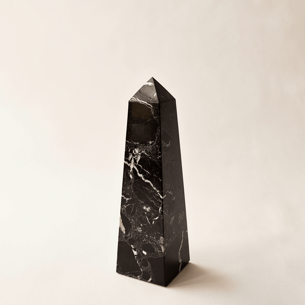 Black marble obelisk on a beige background